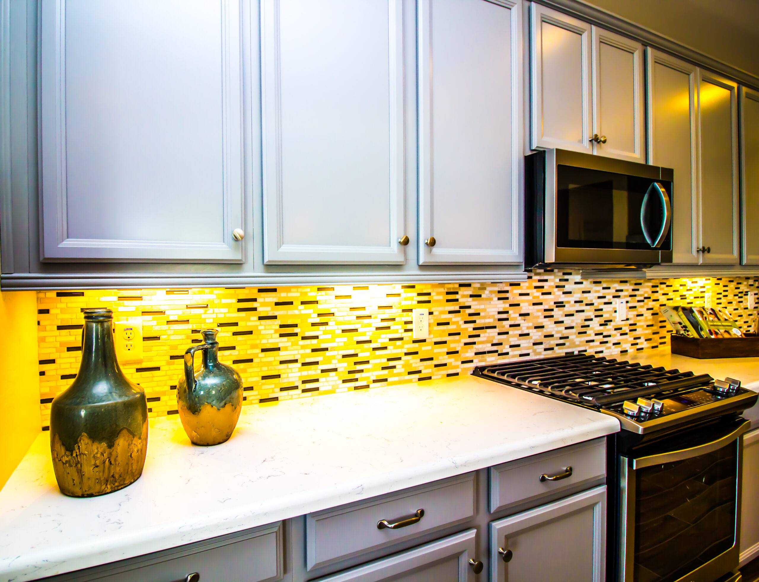 Updated kitchen with over the range microwave, gray cabinets, and tile backsplash