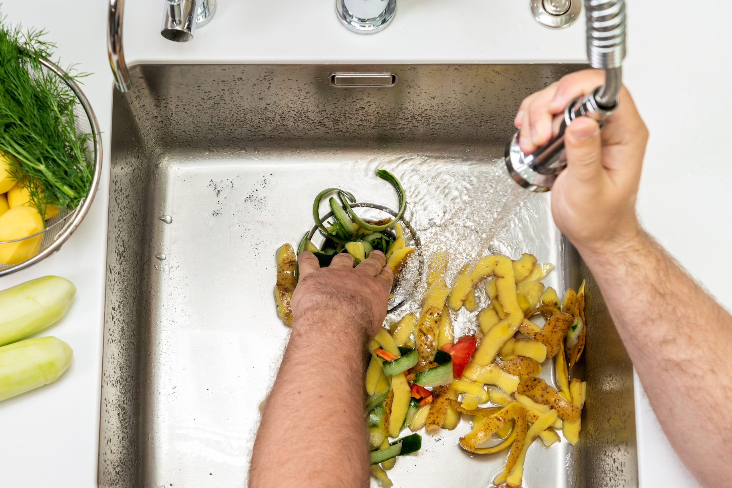 Food waste in the garbage disposal in the kitchen sink and a jet of water